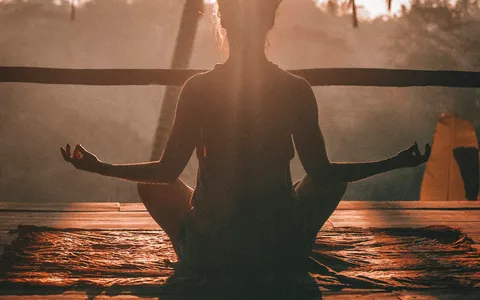 Woman practising yoga at sunrise among palm trees, getting fit in Phuket