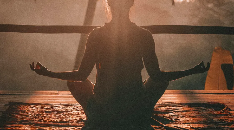 Woman practising yoga at sunrise among palm trees, getting fit in Phuket