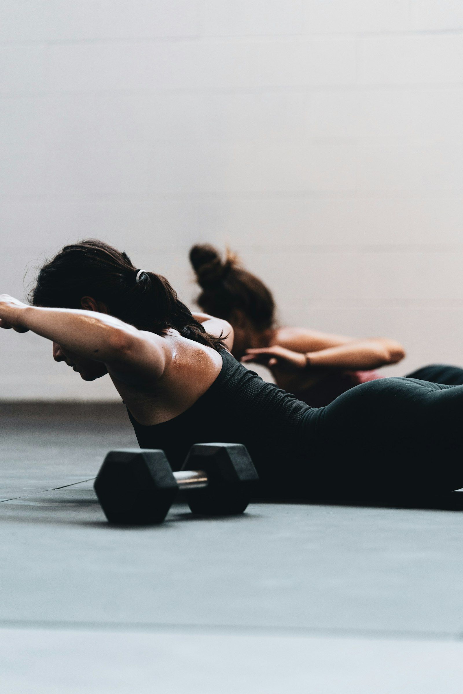Two women strength training together with the guidance of a female personal trainer