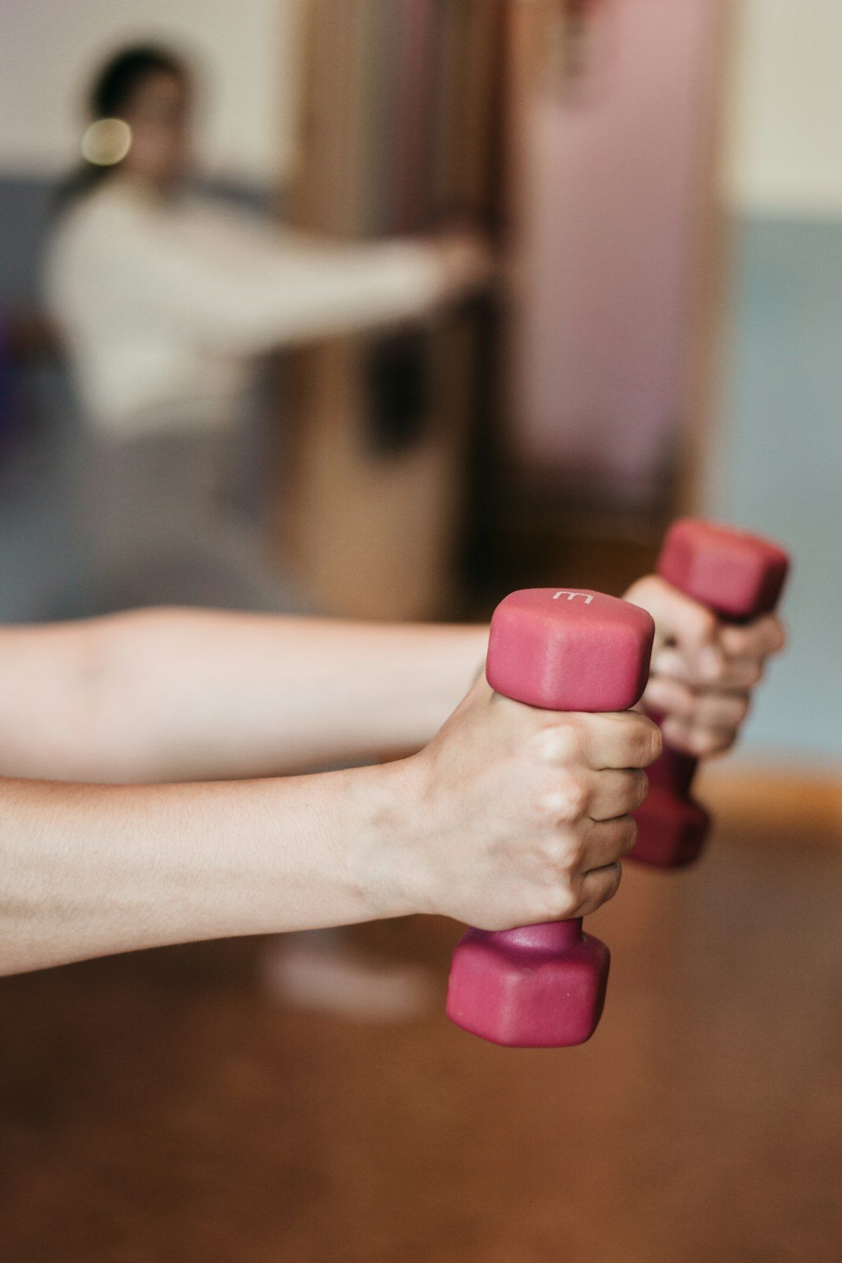 Woman learning a dumbbell strength exercise with good technique in a bright Phuket studio